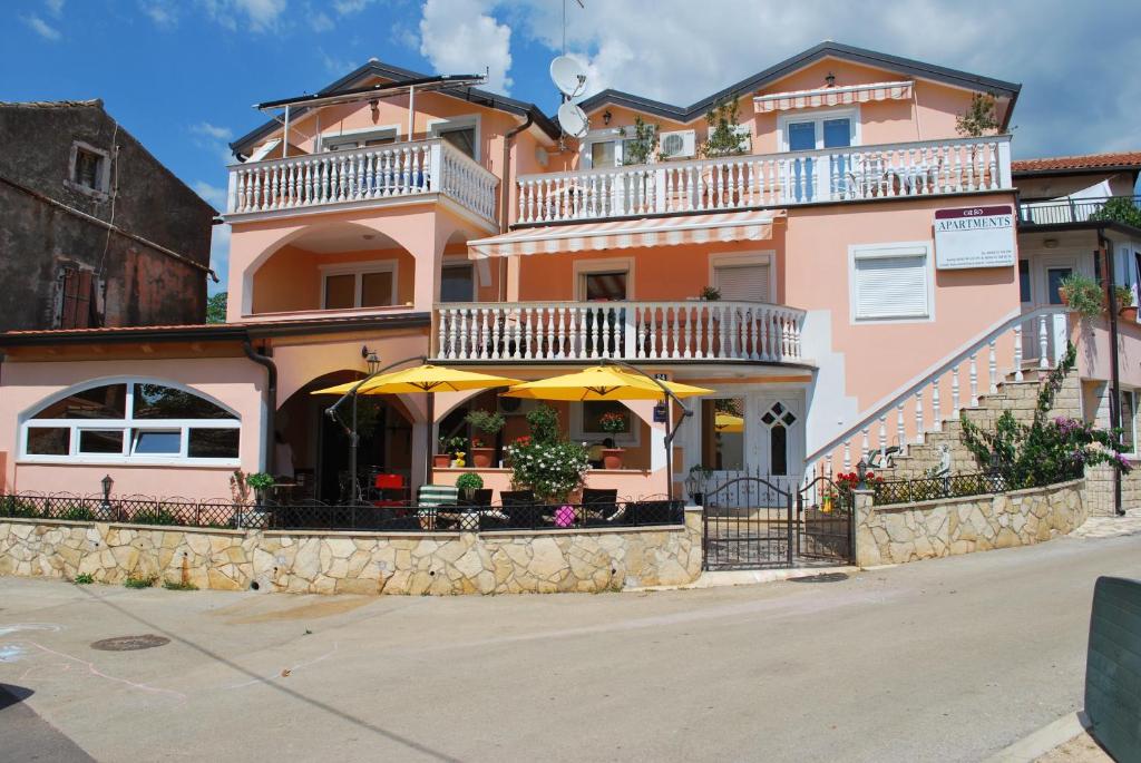 a pink building with an umbrella in front of it at Apartments Maria in Poreč