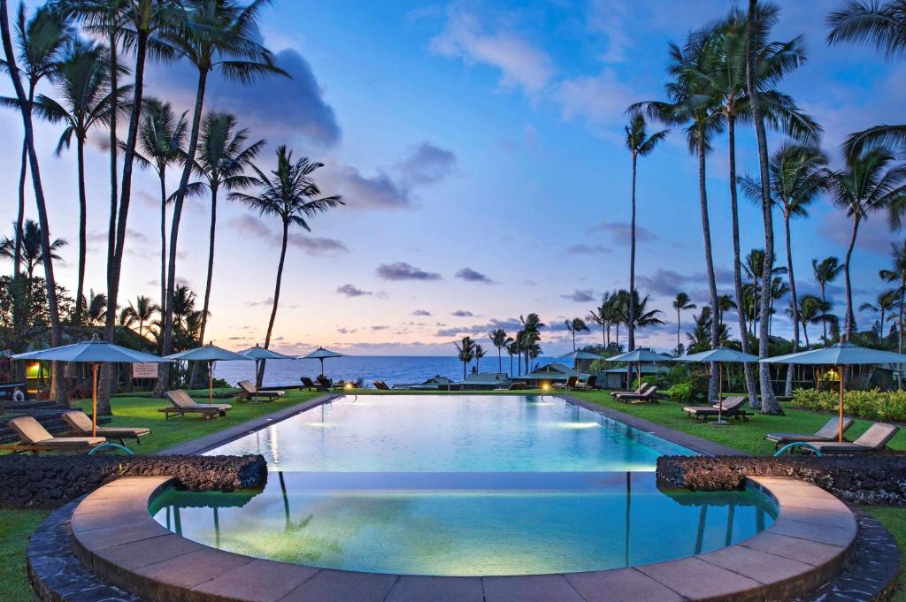 una piscina en un complejo con palmeras y el océano en Hana-Maui Resort, a Destination by Hyatt Residence, en Hana