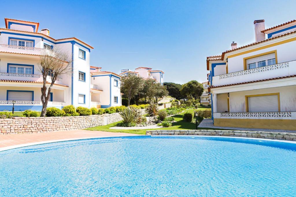 a swimming pool in front of some buildings at The Quiet Loft Praia d'el Rey Golf Resort in Amoreira