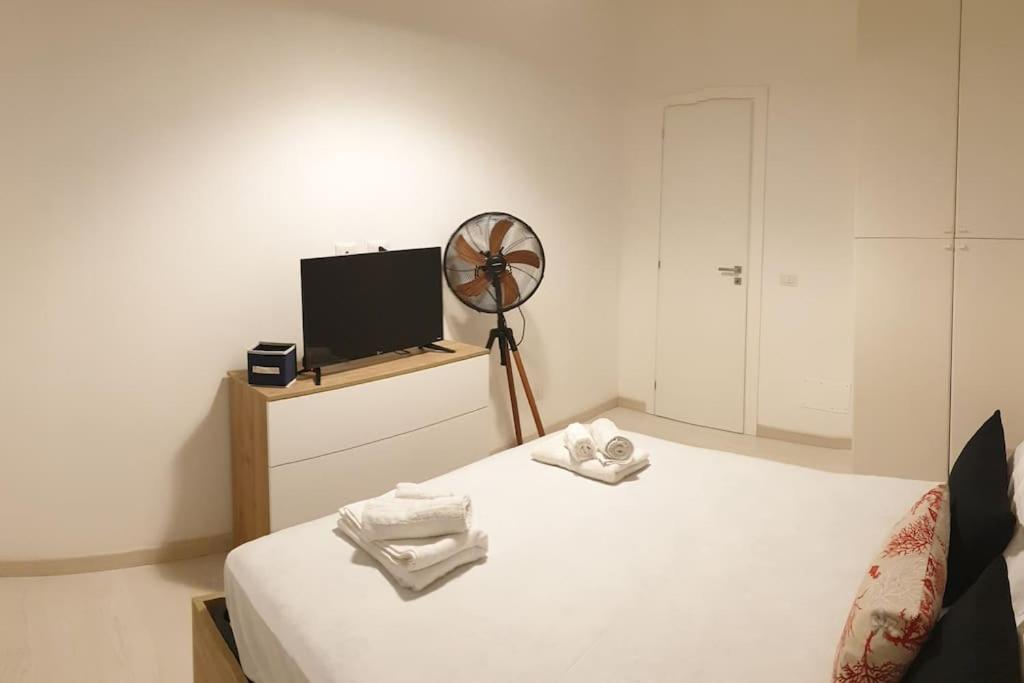 a room with a bed with a fan and a television at RgB_Apartments in Lampedusa