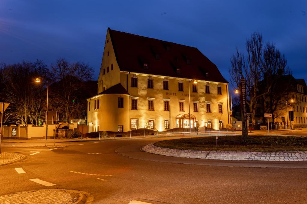 a large building on the side of a street at night at Ringhotel Jägerhof in Weißenfels