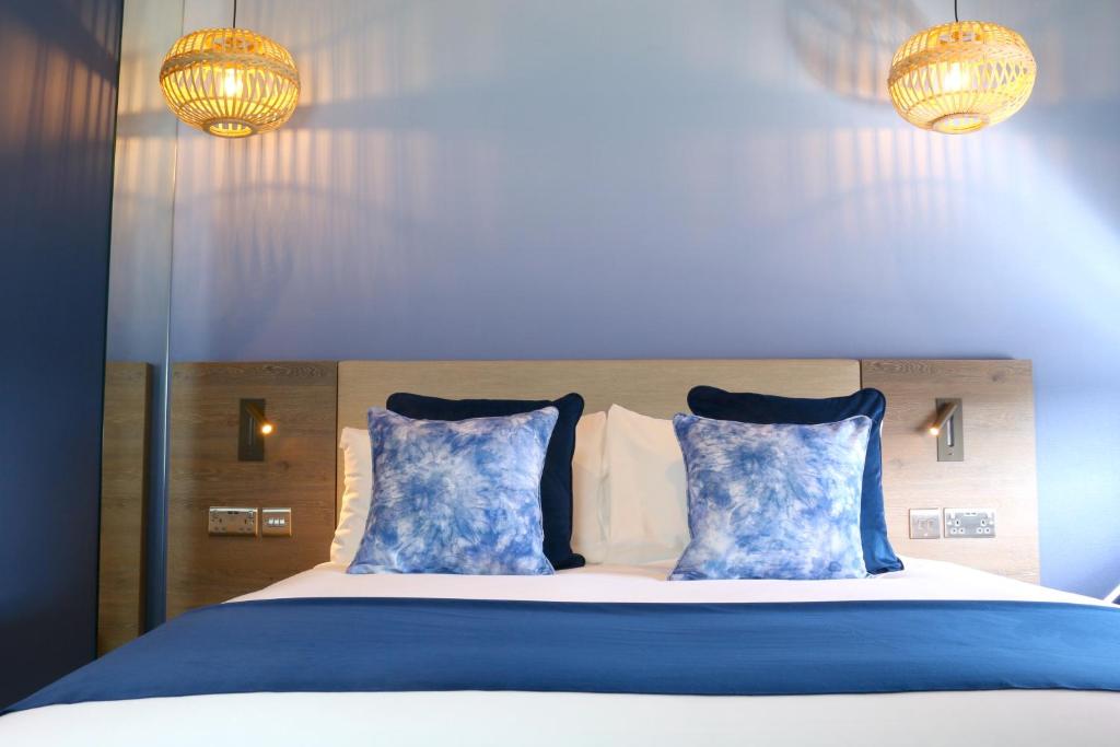 1 cama con almohadas azules y blancas y 2 luces en Hex Wildlife Hotel at Yorkshire Wildlife Park, en Doncaster
