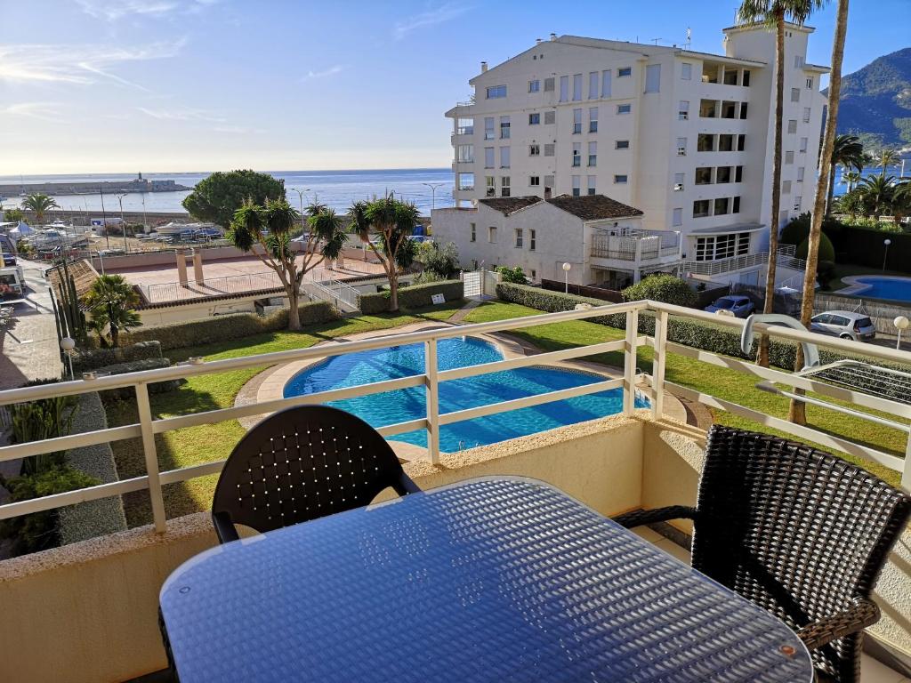 einen Balkon mit einem Tisch, Stühlen und einem Pool in der Unterkunft Acogedor apartamento frente al mar con piscina in Altea