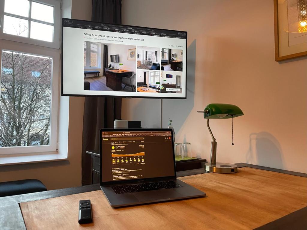 a laptop computer sitting on a desk with a monitor at Office Apartment zentral zur Dortmunder Innenstadt in Dortmund