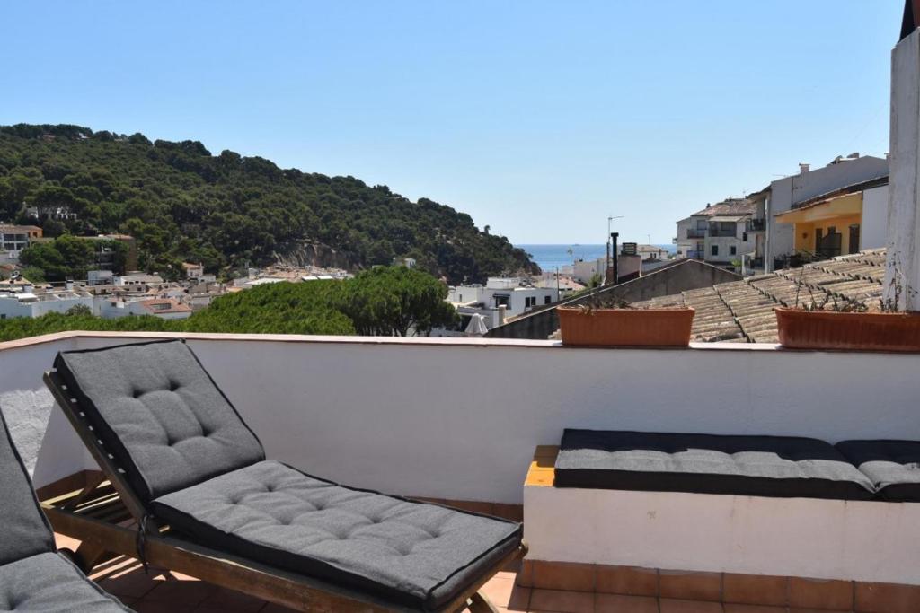 een balkon met een bank en een stoel op een dak bij Balcó de Tamariu in Tamariu