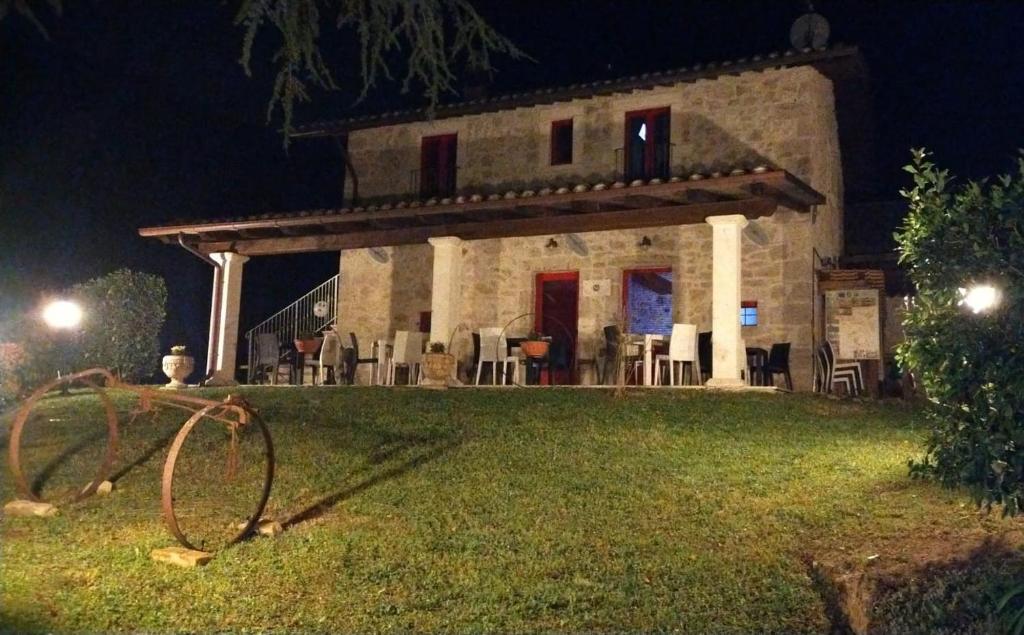 una casa de piedra con sillas en el césped por la noche en B&B Mosca Bianca, en Ascoli Piceno