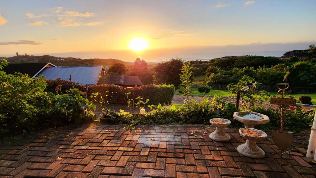 einen Sonnenuntergang über einem Garten mit Vasen auf einer Backsteinterrasse in der Unterkunft Seaview Villa 25 in Shelly Beach