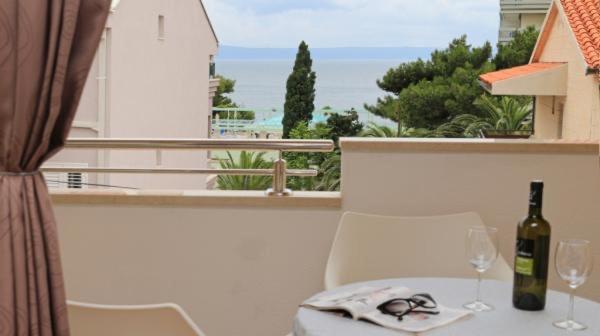 a table with a bottle of wine and glasses on a balcony at Apartmani Abesinac in Makarska