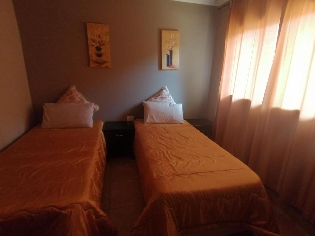 two beds in a small room with a window at Lux contractors accommodation in Bronkhorstspruit