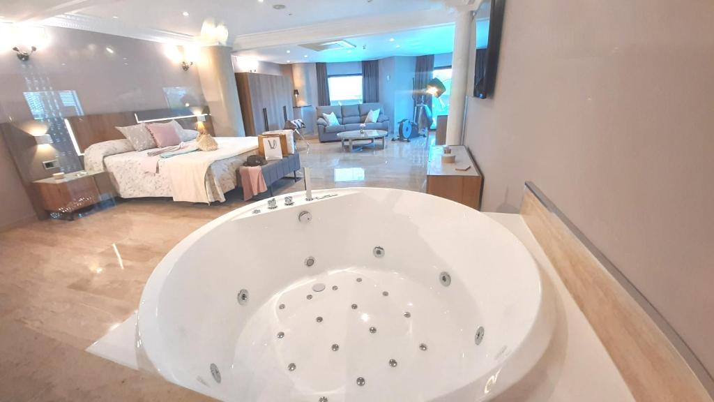 a large white bath tub in a room with a bedroom at Hotel Nueva Plaza in Maliaño