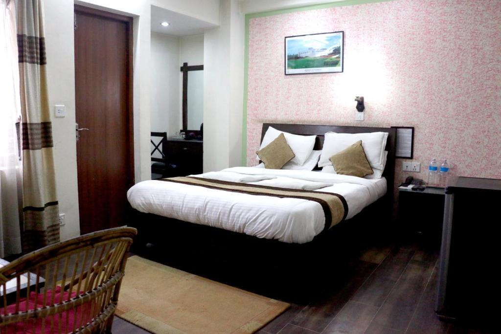 a bedroom with a large bed with white sheets and pillows at Alpine Hotel & Apartment in Kathmandu