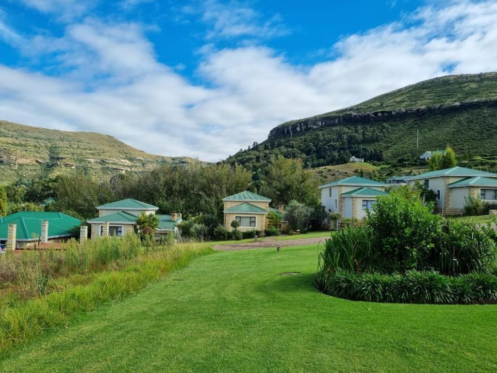 a yard with houses and mountains in the background at Clarens Villas in Clarens