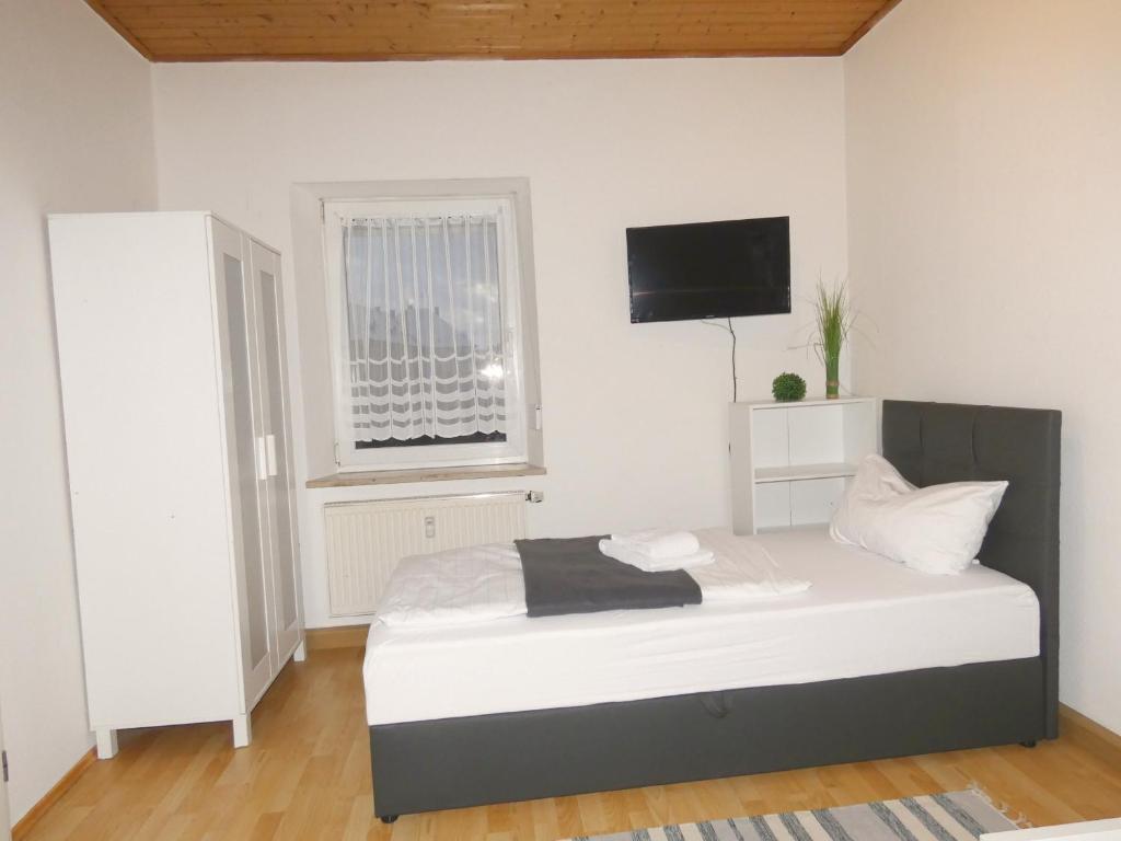 1 dormitorio con 1 cama y TV en la pared en SUNNYHOME Monteurwohnungen und Apartments in Weiden, en Moosbürg