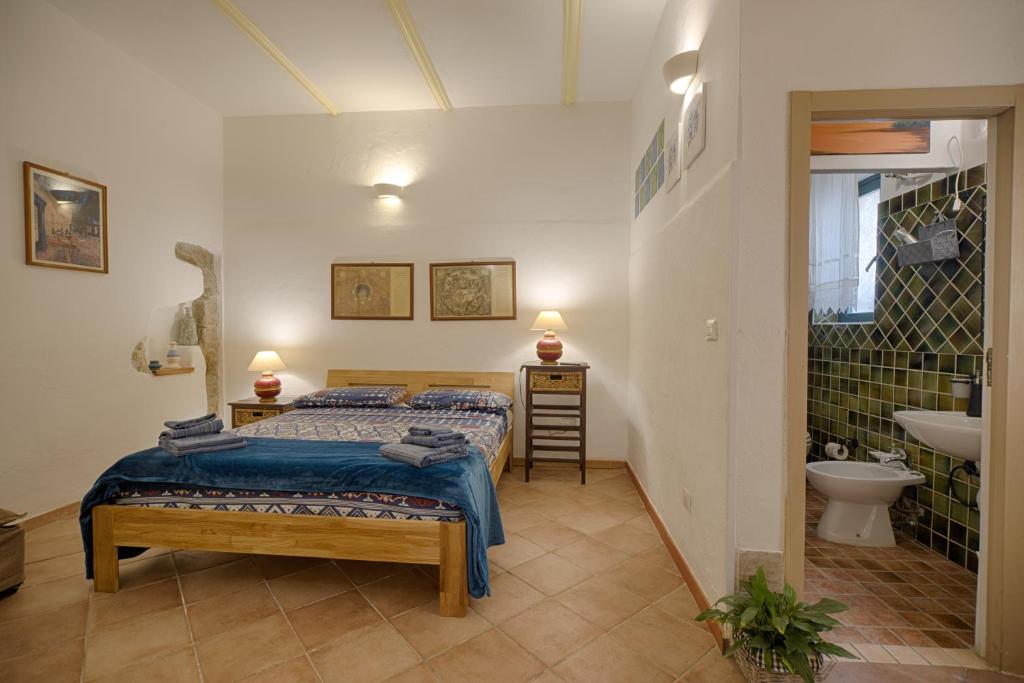 a bedroom with a bed and a bathroom with a sink at La casetta al centro di Olbia in Olbia