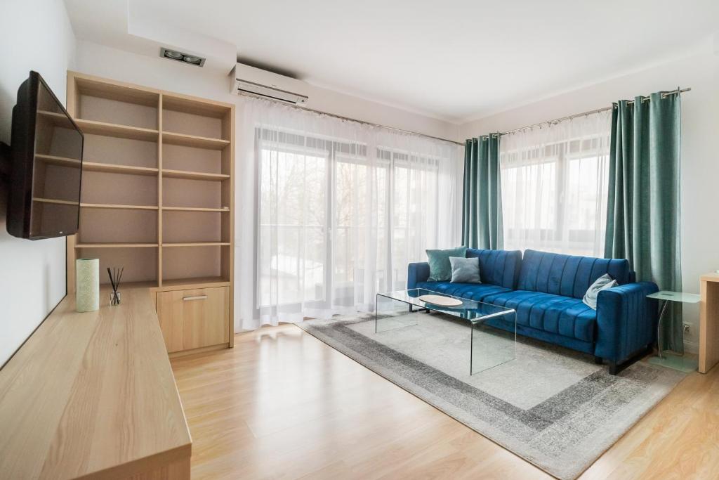 a living room with a blue couch and a tv at Bartycka Elegant Apartment in Warsaw