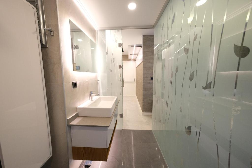a white bathroom with a sink and a mirror at Sky Garden Suites in Adana