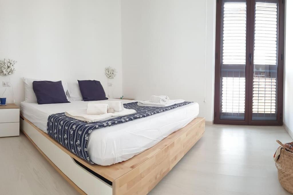 a large bed in a white room with blue pillows at RgB_Apartments in Lampedusa