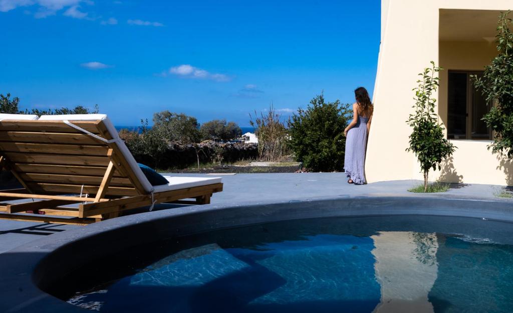 a woman is standing outside of a house next to a swimming pool at Thireon Estate by thireon in Foinikiá