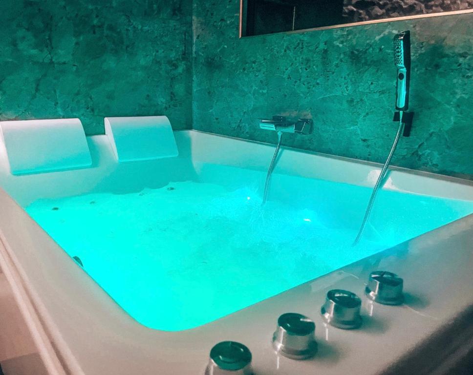 La salle de bains est pourvue d'une baignoire remplie d'eau bleue. dans l'établissement Les Jardins Secrets - Gare & Centre by Apparts Spa Dijon, à Dijon