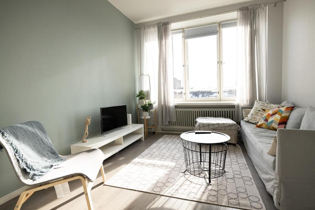 een woonkamer met een bank en een tafel bij 2ndhomes Modern & Central 1BR Top Floor home in Helsinki