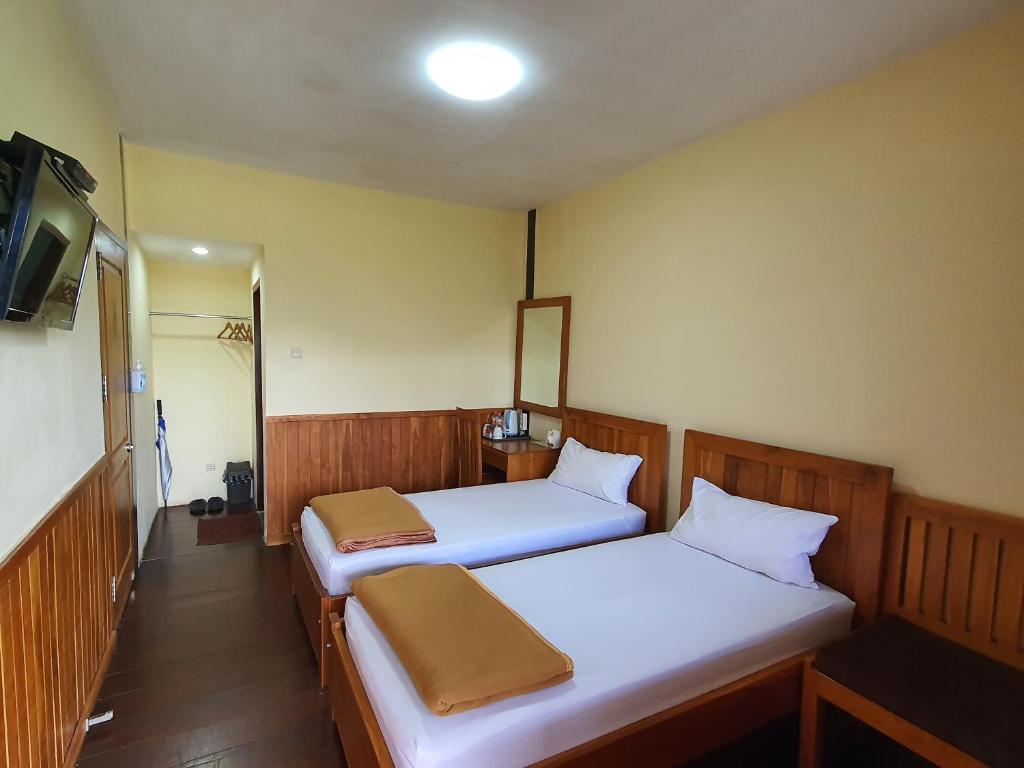 2 łóżka w małym pokoju z telewizorem w obiekcie Nusantara Hotel Sembalun w mieście Sembalun Lawang
