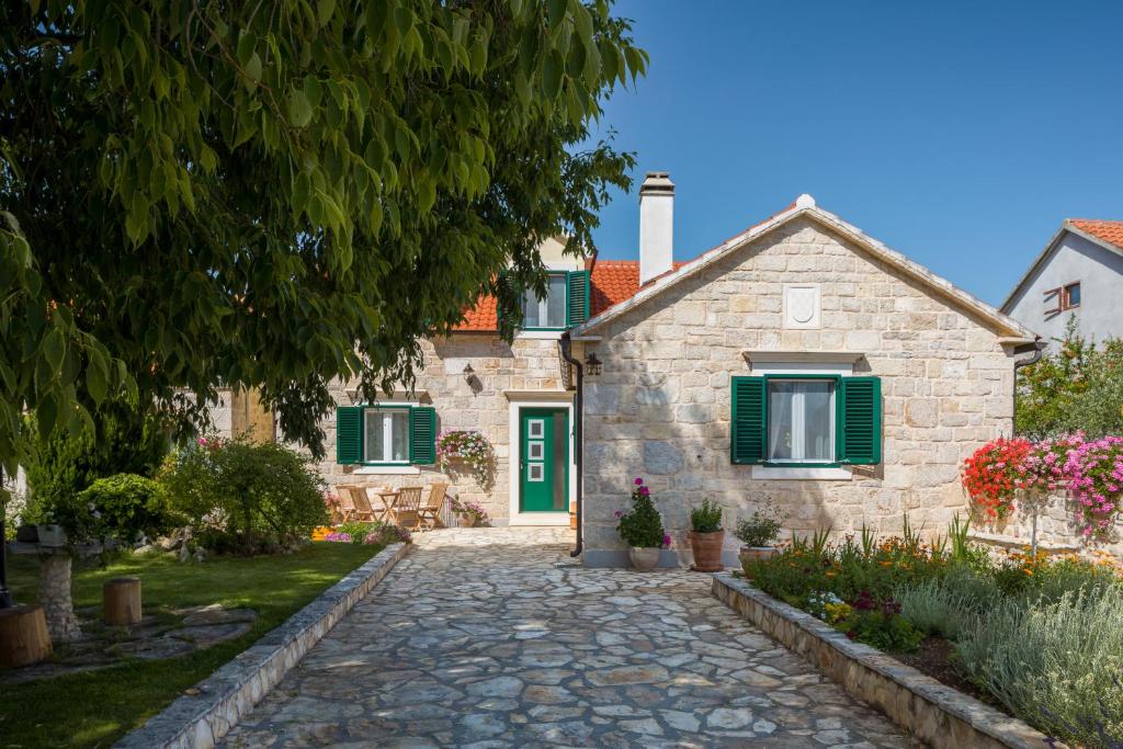 a stone house with green shutters and a stone driveway at Villa Giardino in Drinovci