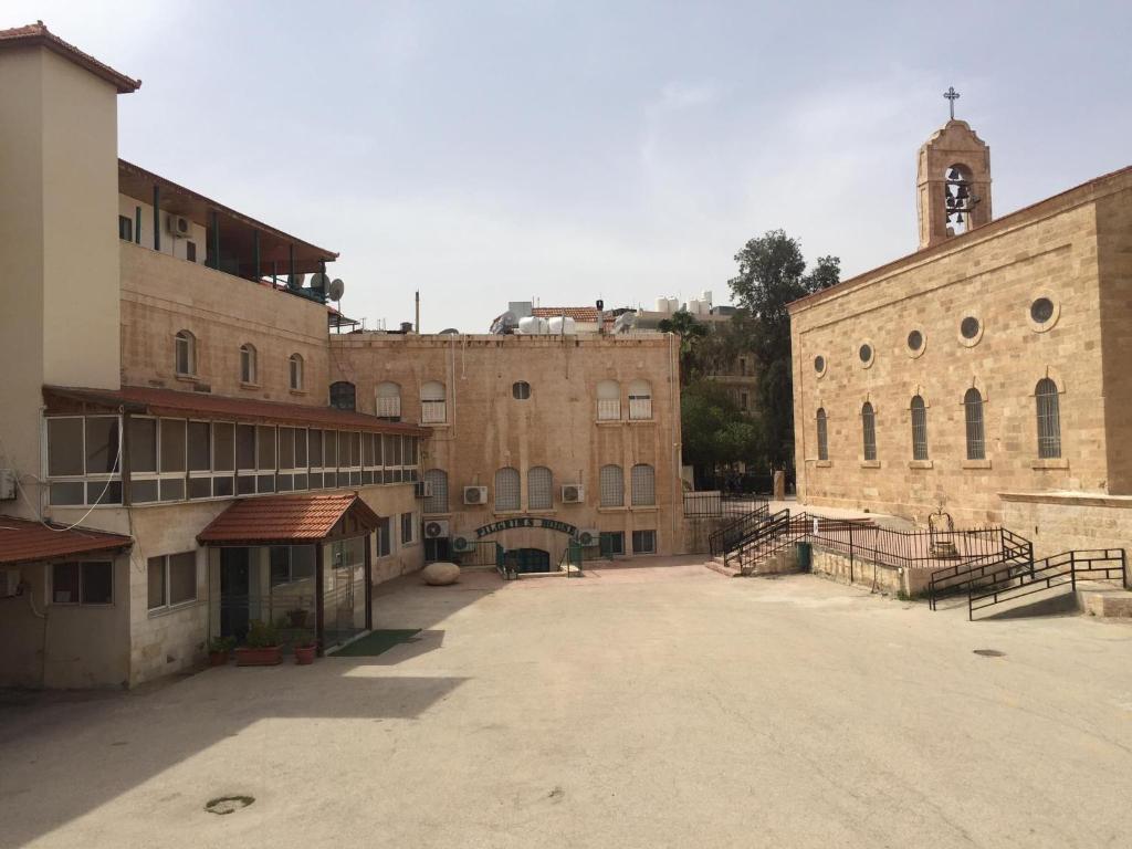 un aparcamiento vacío frente a un gran edificio de ladrillo en Pilgrim's Guest House, en Madaba