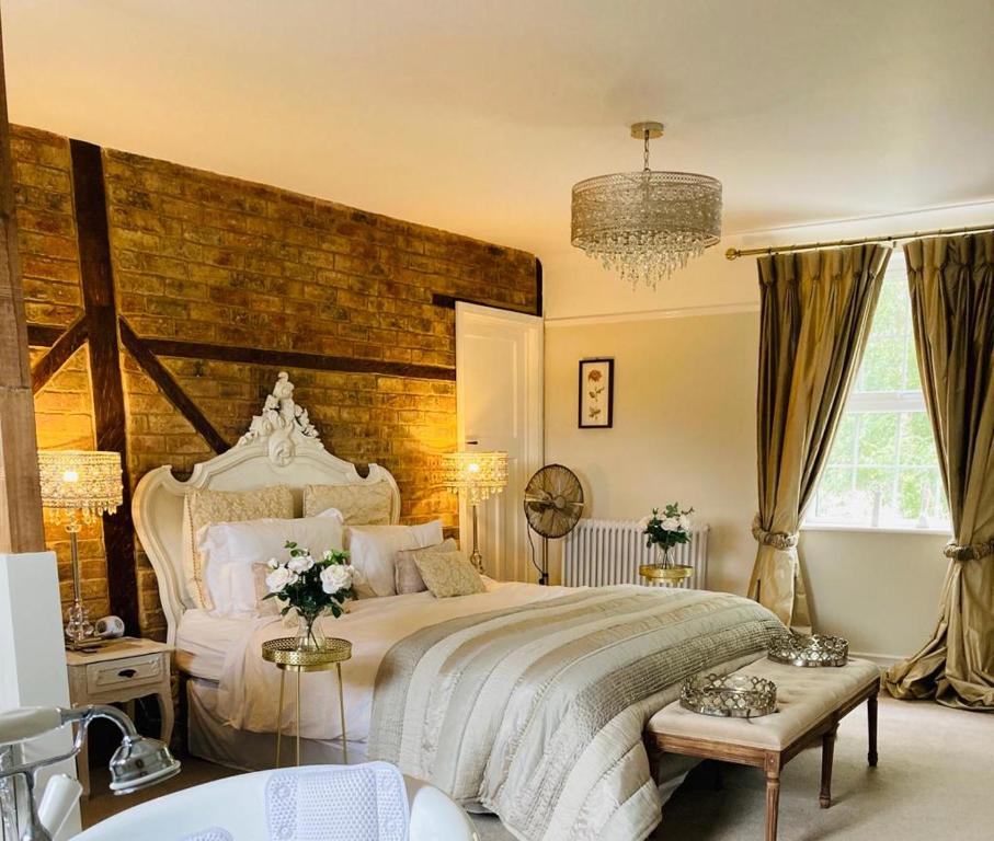 a large bedroom with a large bed and a brick wall at The Willowford in Milton Keynes