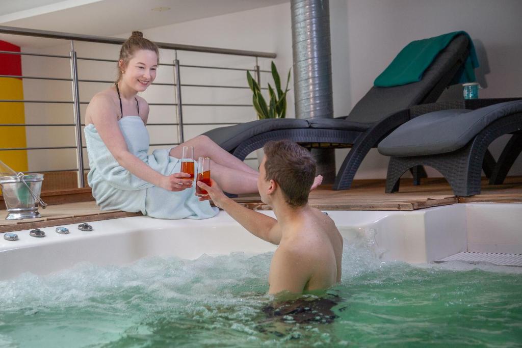 un hombre y una mujer sentados en una bañera tomando bebidas en HOTEL DÜNENLÄUFER Carolinensiel, en Carolinensiel