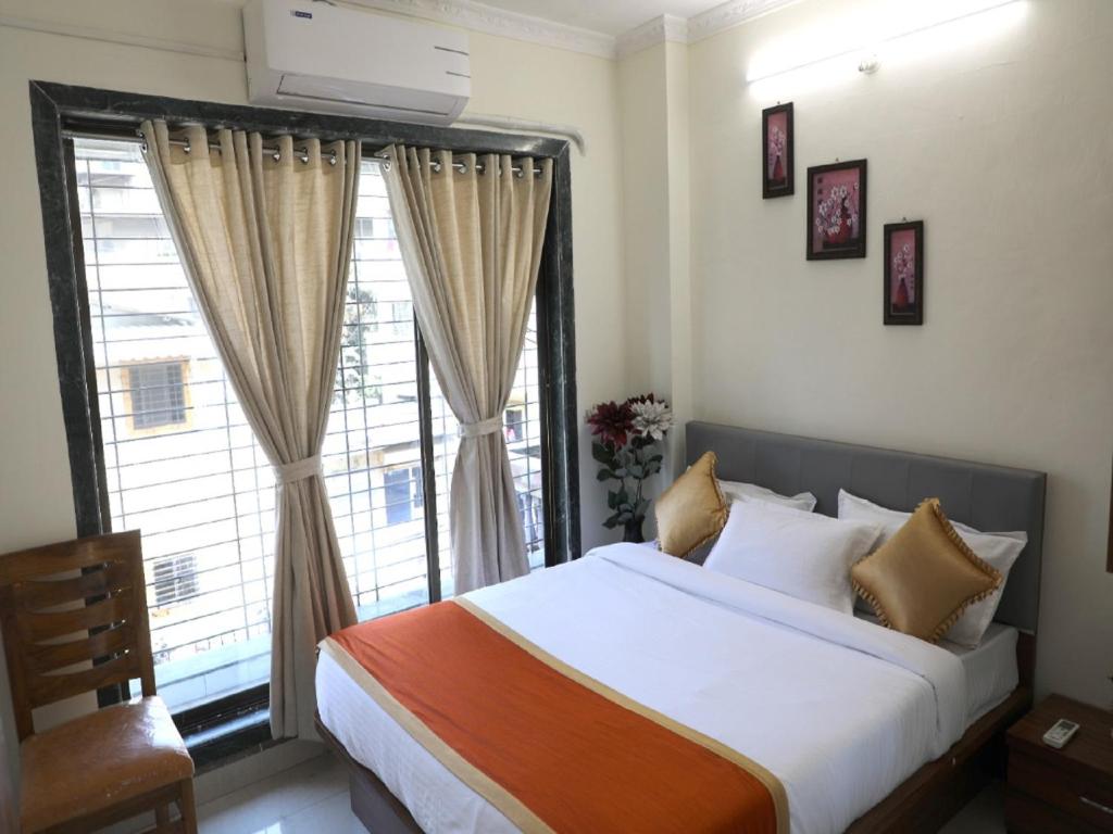 a bedroom with a bed and a large window at Hotel Satyam Residency in Navi Mumbai