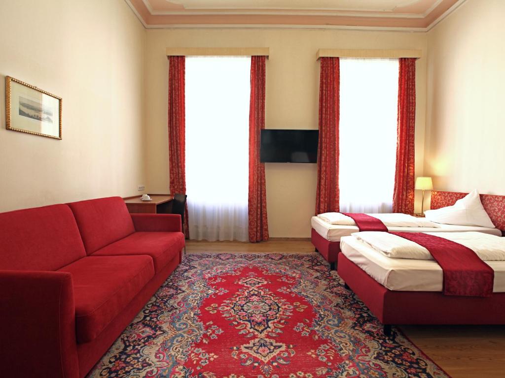 Una habitación de hotel con dos camas y un sofá rojo. en HPA Hotel Andreas, en Viena