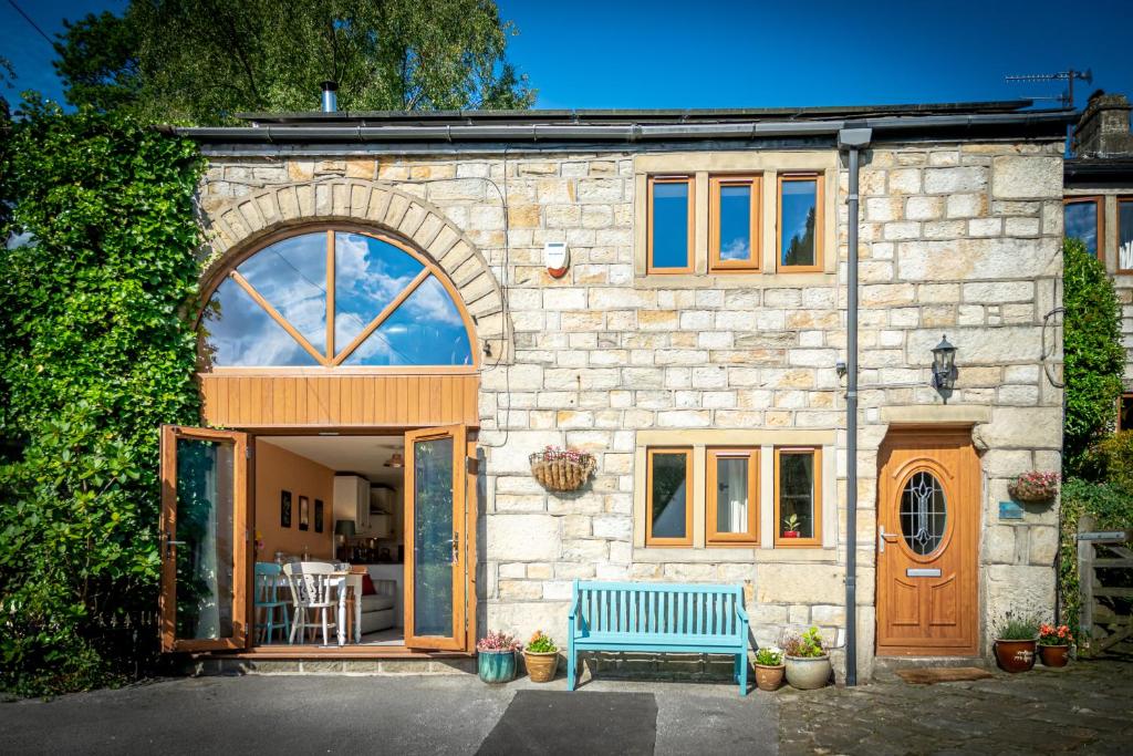 a stone house with a blue bench in front of it at Woodbottom Farm - A Splendid Yorkshire Getaway in Todmorden