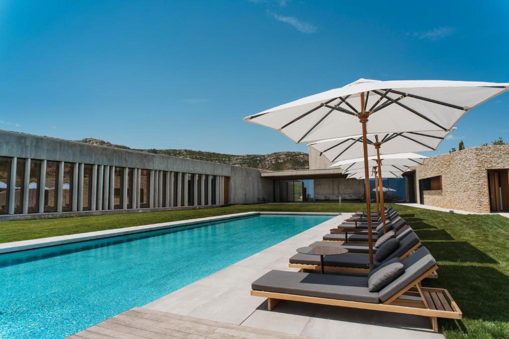 Barraca de Aguas Vivas的住宿－La Galiana Golf Resort - Adults Only，游泳池旁的一组带遮阳伞的躺椅