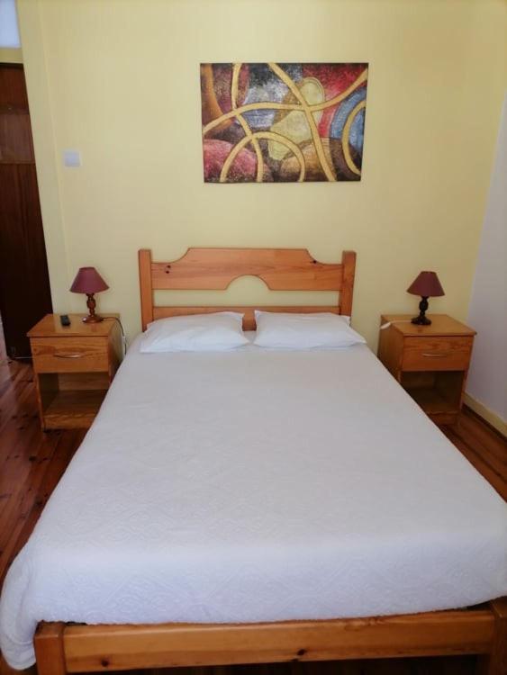 1 dormitorio con 1 cama blanca grande y 2 mesitas de noche en PENSÃO AVENIDA, en Penacova