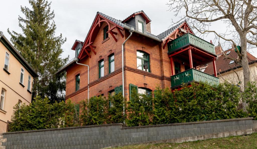 イェーナにあるFerienwohnung Jenzigblickの緑のバルコニー付きの大きな赤レンガ造りの家