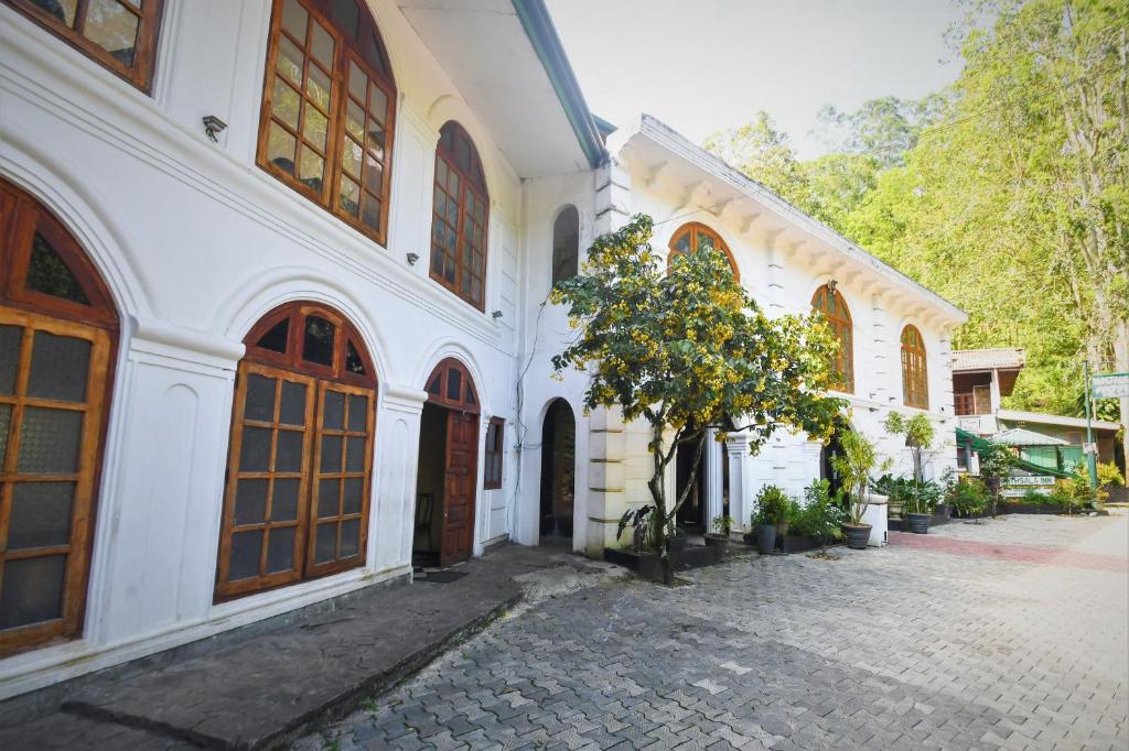 un edificio blanco con un árbol en un patio en Wathsala Inn, en Nallathanniya