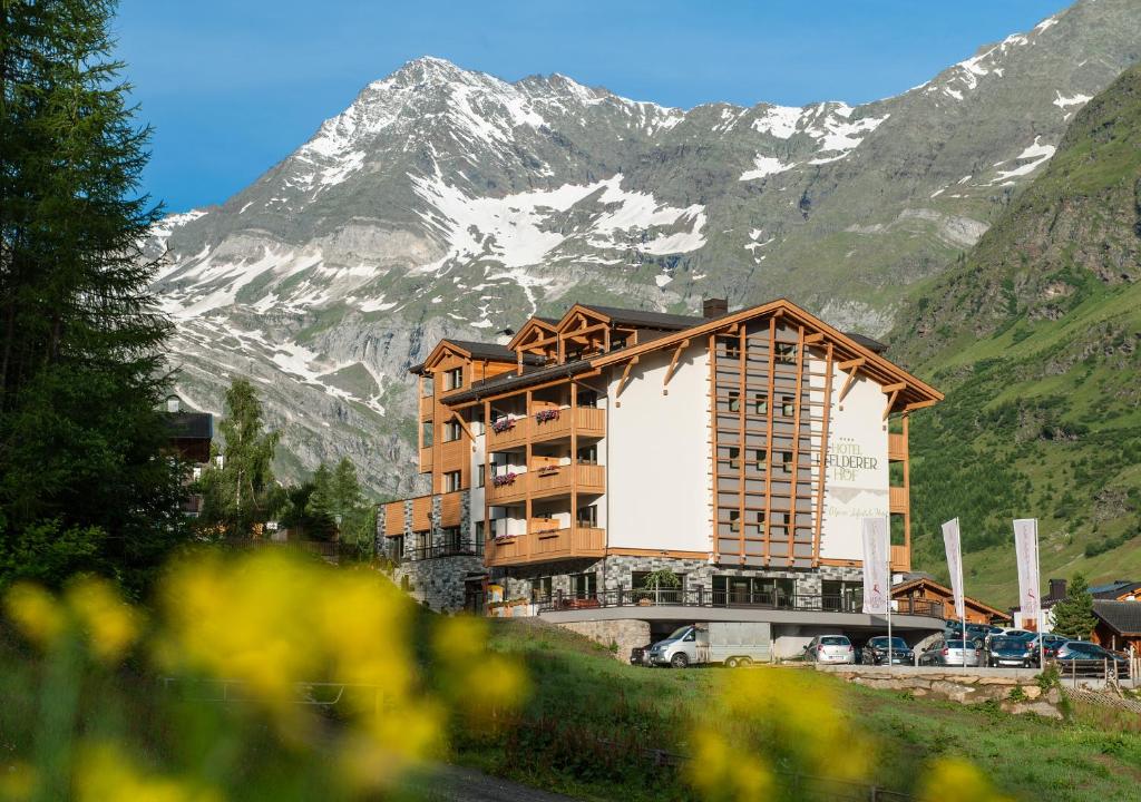 un edificio con una montaña en el fondo en Hotel Pfeldererhof Alpine Lifestyle, en Moso in Passiria