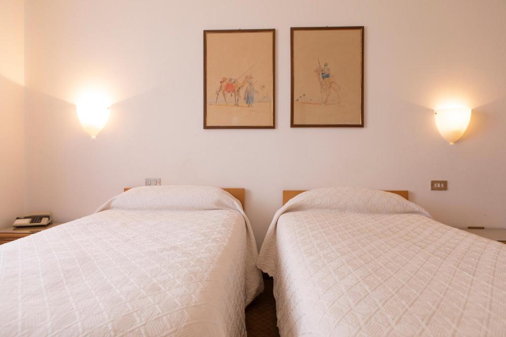 two beds in a room with three pictures on the wall at Hotel Due Mori in Cittadella