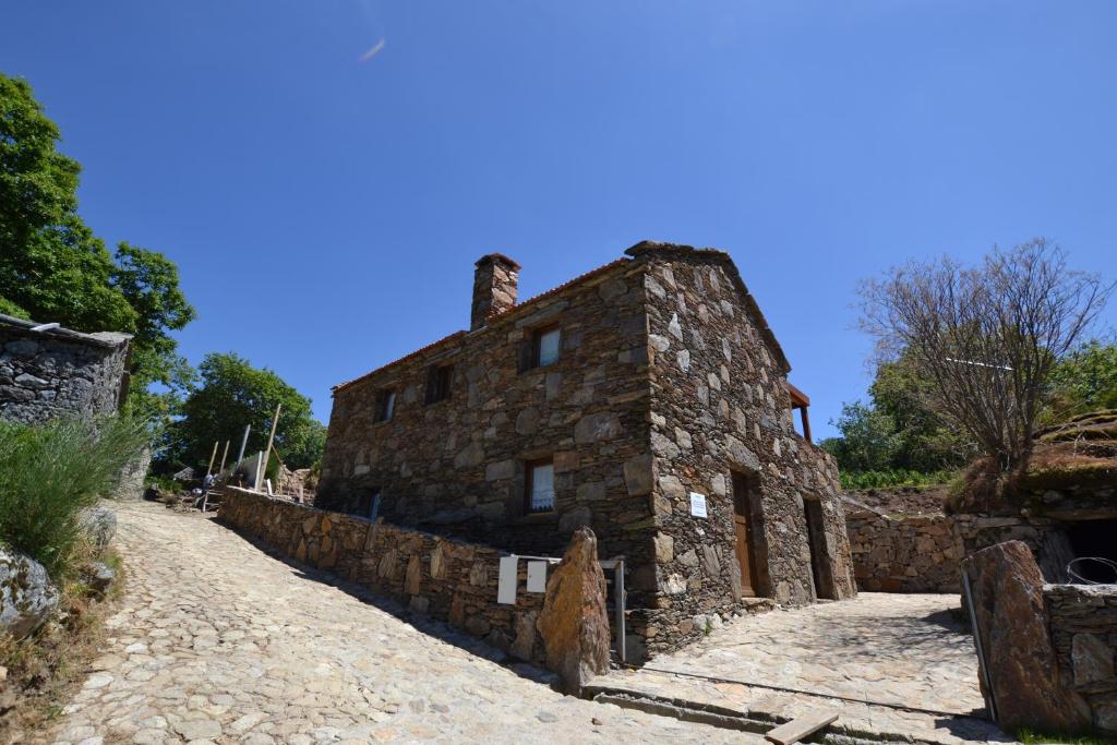 un viejo edificio de piedra en un camino de tierra en Casas de Xisto, Branda da Aveleira, en Melgaço