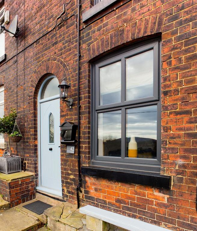 a brick building with a window and a white door at THE VIEW! in Delph