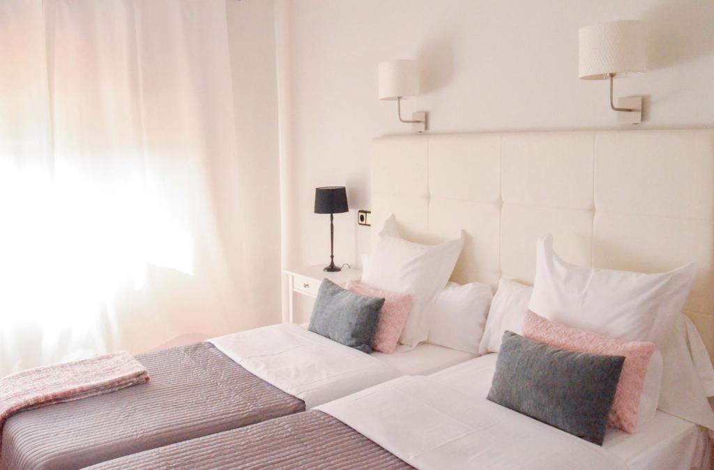 1 dormitorio blanco con 1 cama con 2 almohadas en Hostal Carlos V, en Puebla de Sanabria