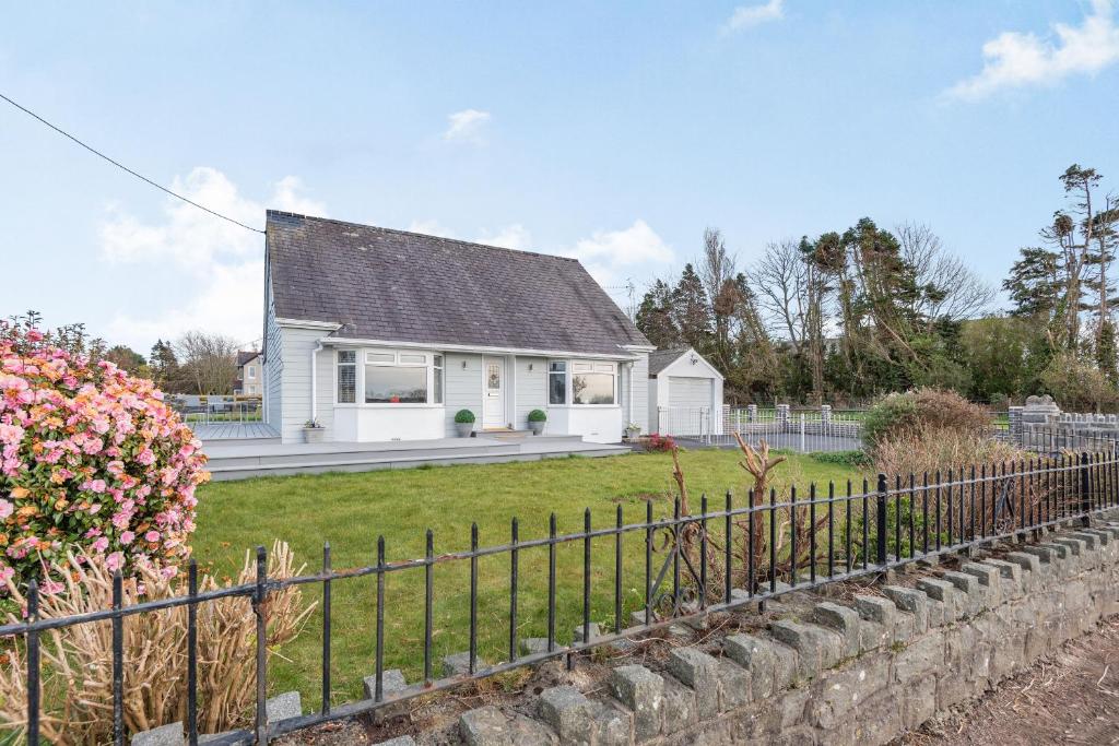uma casa branca com uma cerca à frente. em Bryn Derw em Caernarfon