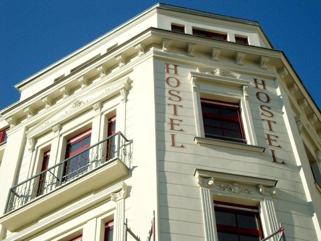 萊比錫的住宿－Sleepy Lion Hostel & Apartments Leipzig，白色的建筑,上面有酒店标志