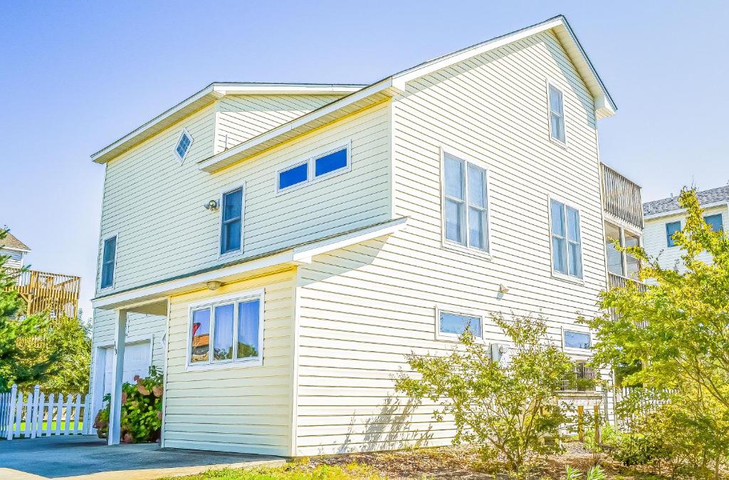 a white house with blue windows at Coffee to Cocktails - Duck, Ocean Dunes, Ocean View, 400 Yds to Beach, Hot Tub, Pets OK in Duck