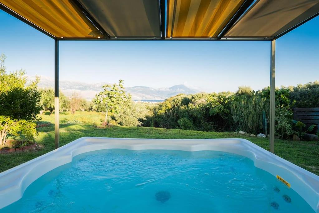 a hot tub in a backyard with a view of the mountains at Dreamy Wooden Cottage Lixouri in Lixouri