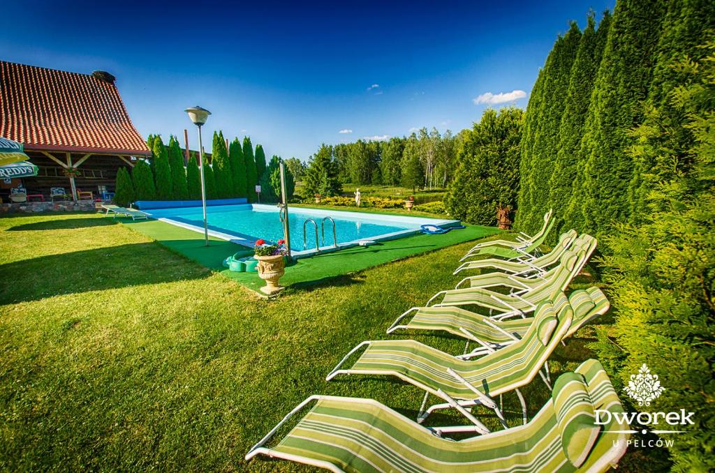 a row of lawn chairs next to a swimming pool at Agroturystyka "Dworek u Pelców" in Ryn