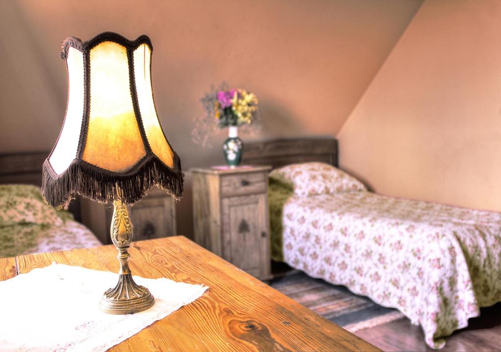 una lámpara en una mesa en un dormitorio con 2 camas en Zajazd Pod Kogutkiem, en Busewo