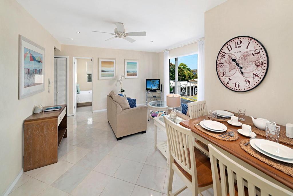 a dining room and living room with a large clock on the wall at Lantana 42 in Saint James