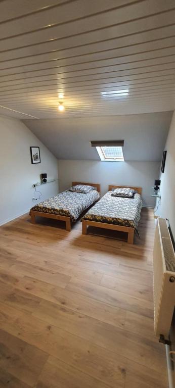 two beds in a large room with wooden floors at T2 tout confort pour 6 couchages in Hazebrouck