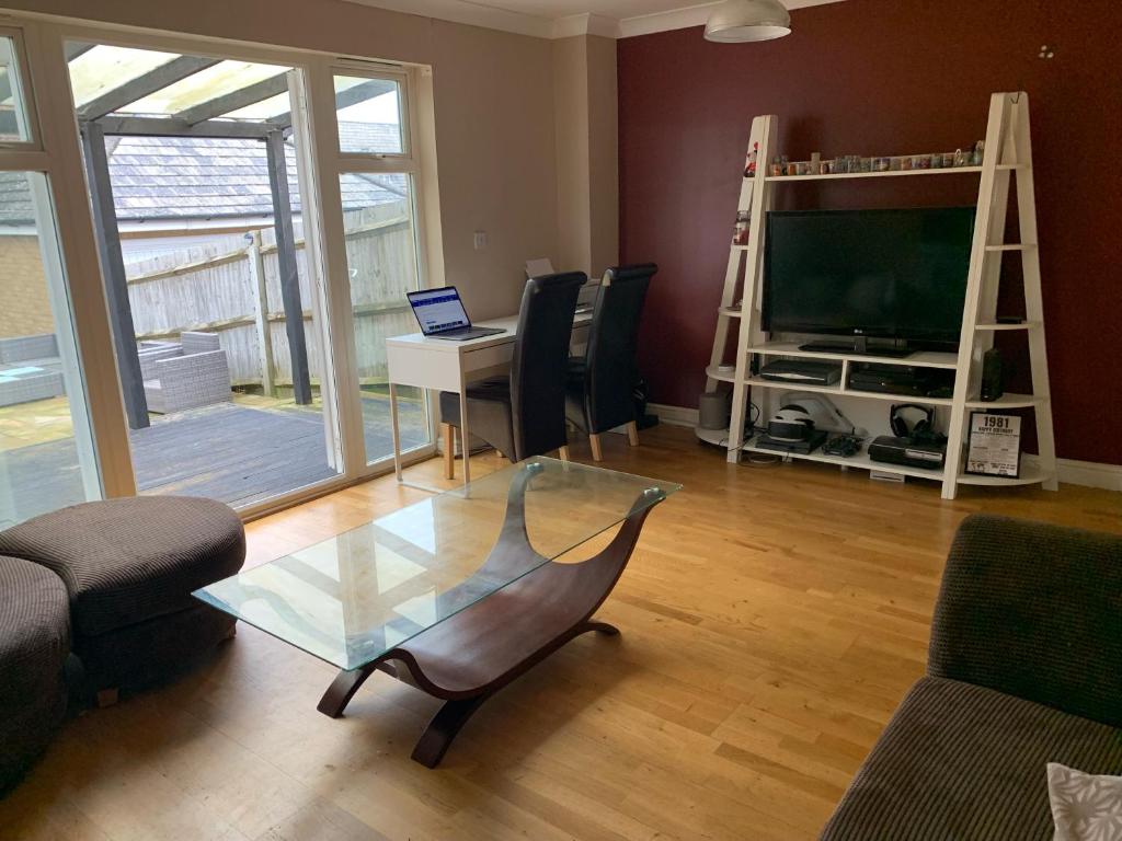 a living room with a glass coffee table and a television at Entire Family Entertainment Holiday Home - 3 x Floors - Free Parking - Games Room - Private Garden - Workspace and Wifi 112mb - Self Check-in in Ashford